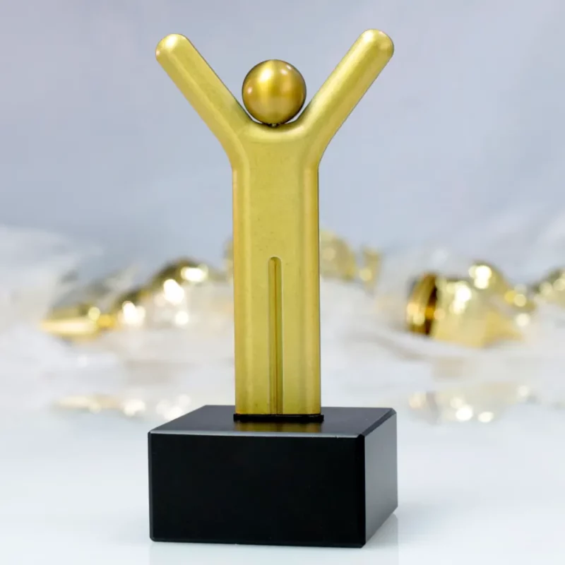 A stylised trophy shaped like a figure with raised arms, crafted in gold.